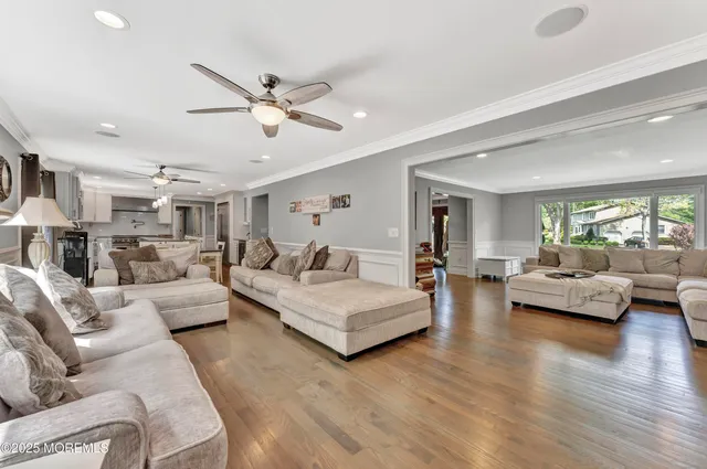 a living room with furniture kitchen view and a wooden floor