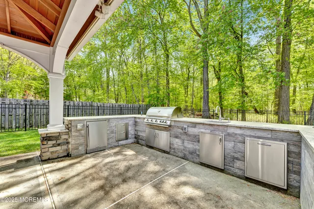 a view of a kitchen with a sink and dishwasher a barbeque with wooden fence