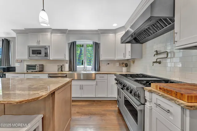 a kitchen with stainless steel appliances granite countertop a sink stove and cabinets