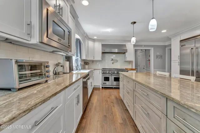 a large kitchen with stainless steel appliances granite countertop a lot of counter space and a sink