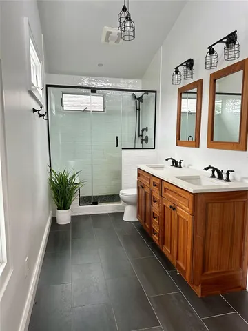 a spacious bathroom with a double vanity sink a large mirror and a shower