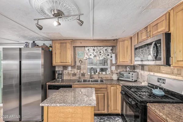 a kitchen with stainless steel appliances granite countertop a sink stove and refrigerator