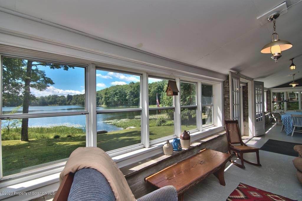 292 Loomis Lk Road Hop Bottom, PA 18824 - Photo 20 of 76 a living room with patio furniture and a floor to ceiling window