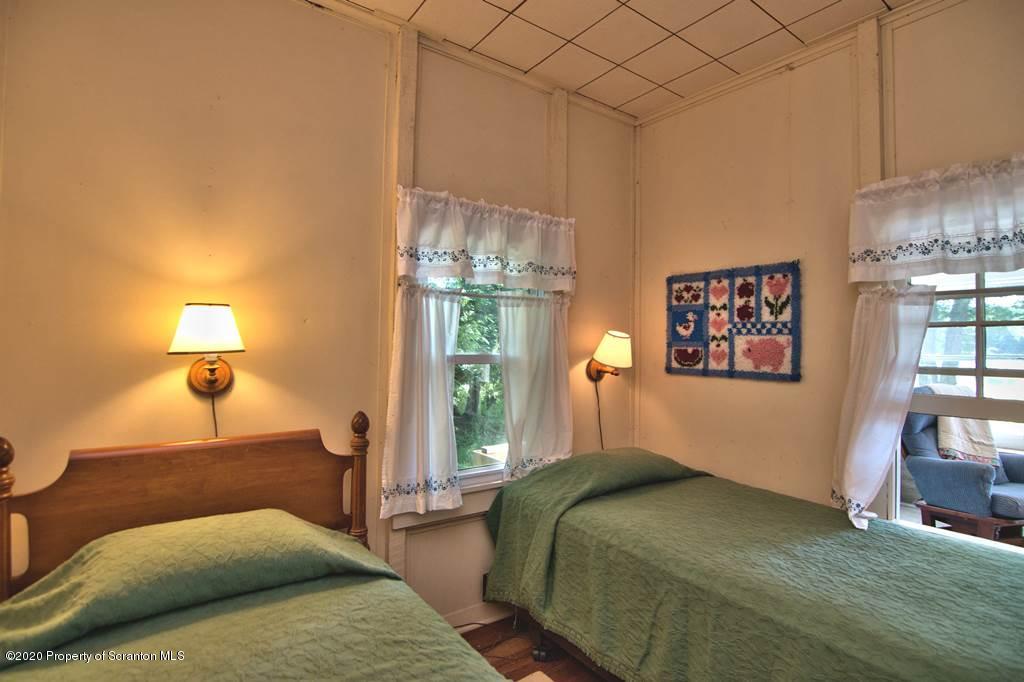 292 Loomis Lk Road Hop Bottom, PA 18824 - Photo 30 of 76 a bedroom with a bed and a lamp with table