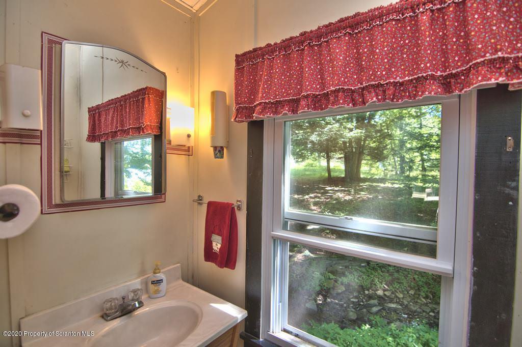 292 Loomis Lk Road Hop Bottom, PA 18824 - Photo 33 of 76 a bathroom with a sink and a large mirror next to a window
