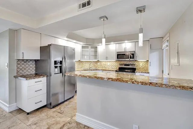 a kitchen with stainless steel appliances granite countertop a refrigerator a sink and a stove