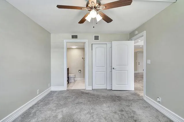a view of an empty room and chandelier fan