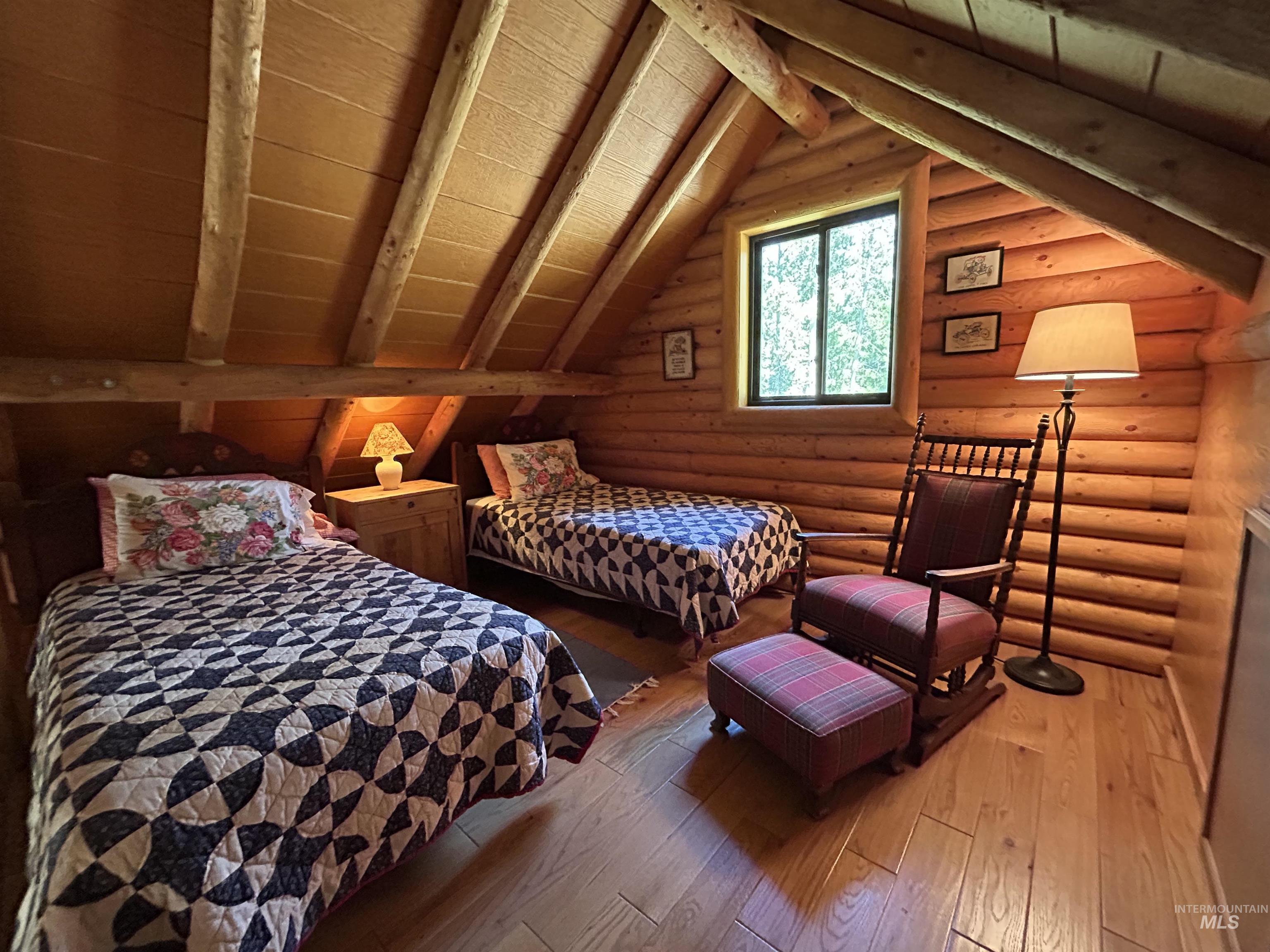 35 Sawtooth Way Stanley, ID 83278 - Photo 26 of 36 Log cabin interior featuring a window, wood-finish flooring, exposed wood beams, and log walls