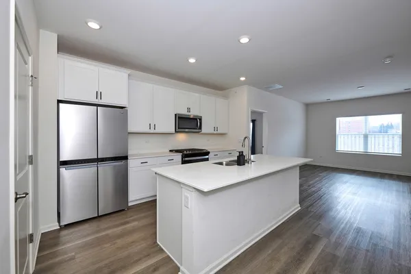 a kitchen with a refrigerator a sink dishwasher and a stove with wooden floor