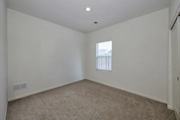 a view of an empty room with closet and a window