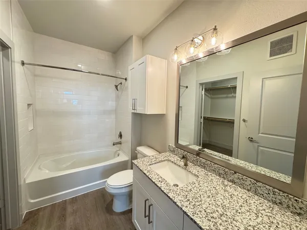 a bathroom with a granite countertop sink toilet and shower