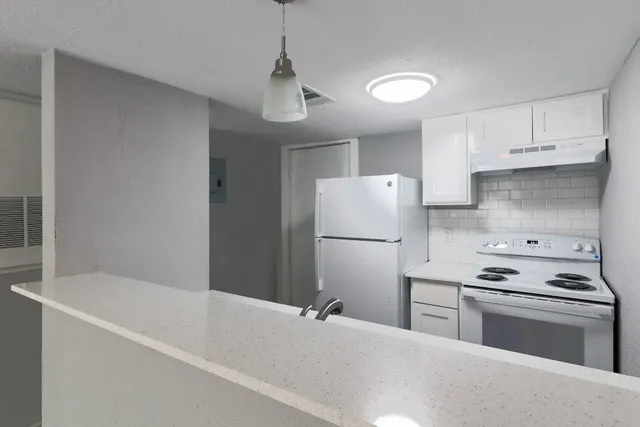 a kitchen with a refrigerator a stove and white cabinets