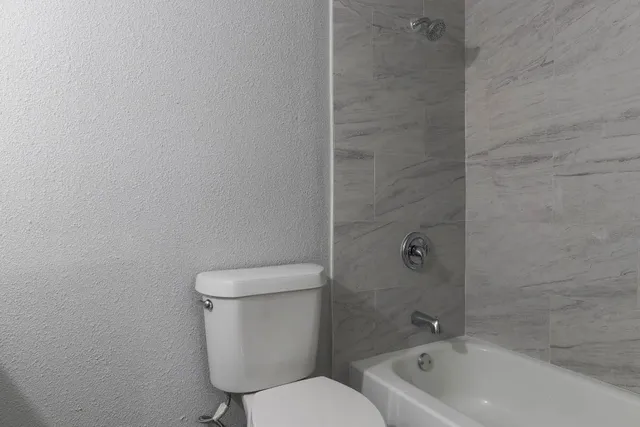 a white toilet sitting next to a bath tub