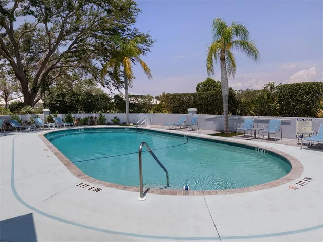 a view of a swimming pool with a yard and palm trees