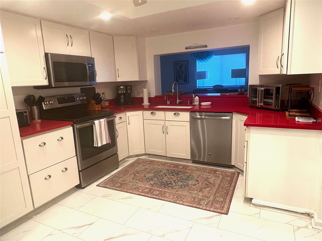 1000 Riverside Drive, Unit B104 Palmetto, FL 34221 - Photo 12 of 36 a kitchen with stainless steel appliances kitchen island granite countertop a stove top oven a sink a counter space and cabinets