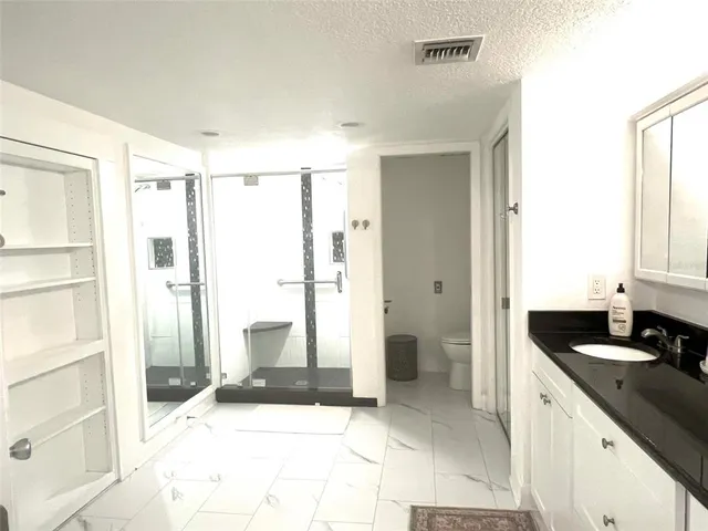 a bathroom with a granite countertop sink toilet a mirror and shower