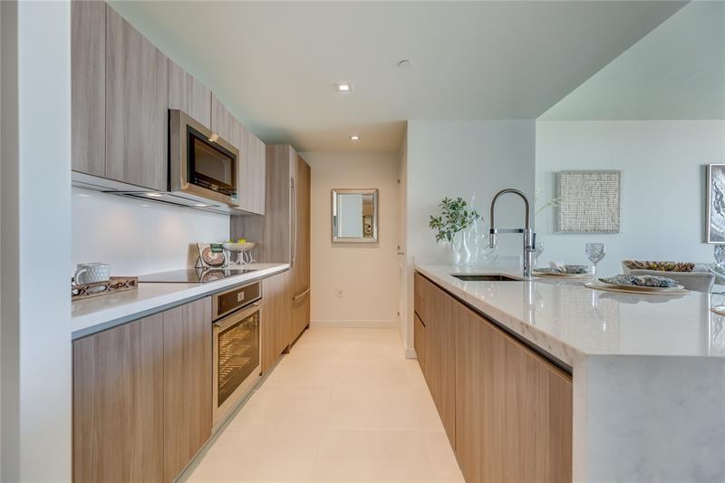 401 North Birch Road, Unit 1012 Fort Lauderdale, FL 33304 - Photo 15 of 44 a large kitchen with stainless steel appliances granite countertop a sink and dishwasher a stove top oven with wooden floor