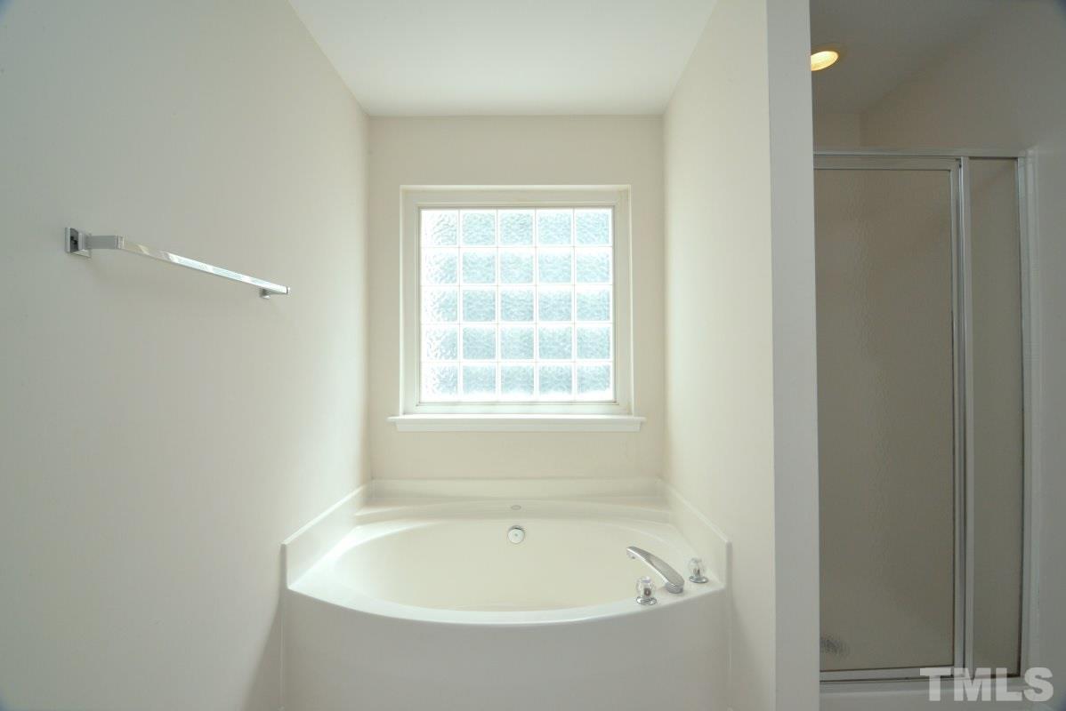 8303 Rubblestone Path Raleigh, NC 27613 - Photo 18 of 25 a white bath tub sitting in a bathroom next to a window