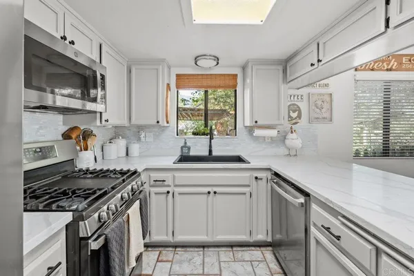 a kitchen with cabinets appliances a sink and a window