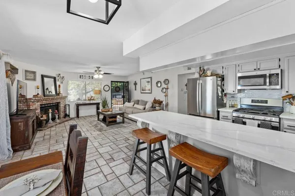 a kitchen with stainless steel appliances granite countertop a stove refrigerator a dining table and chairs with wooden floor