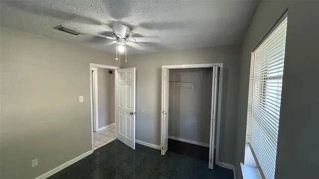 a view of an empty room and closet area with fan