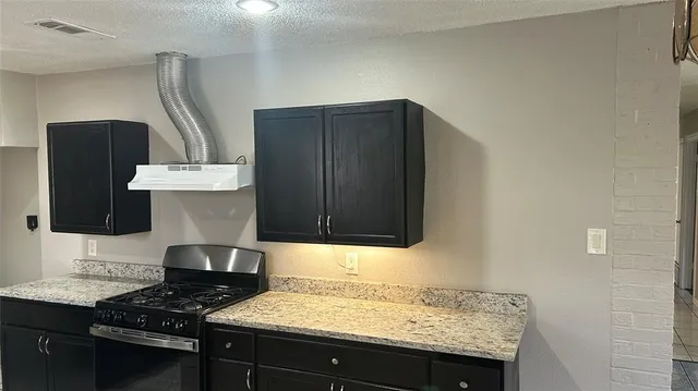 a kitchen with granite countertop a sink a stove and a wooden cabinets