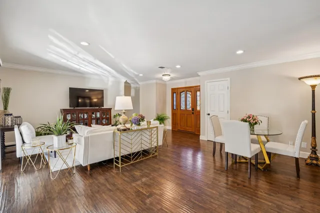 a kitchen with stainless steel appliances granite countertop a stove top oven a sink dishwasher a dining table and chairs with wooden floor