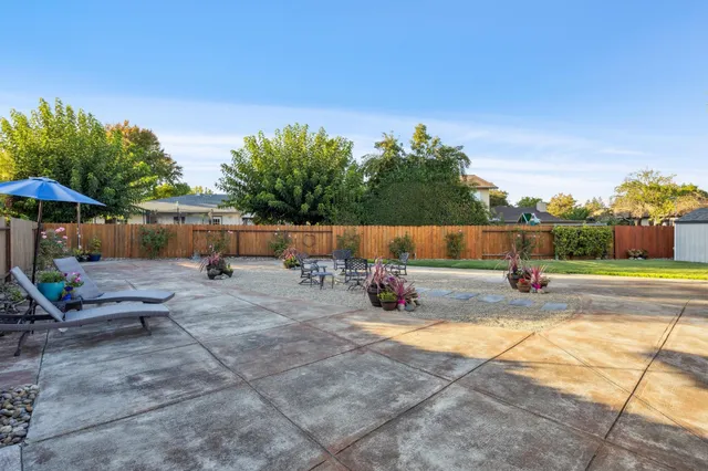 a view of a patio with table and chairs and potted plants with wooden fence