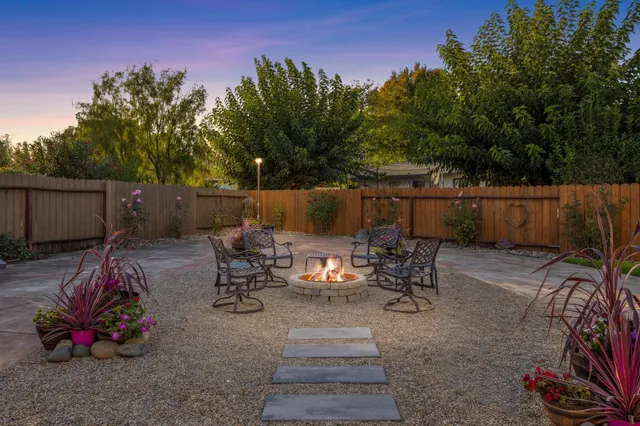 a view of a patio with table and chairs potted plants and a large tree