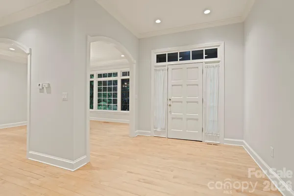 a view of an empty room with wooden floor and windows
