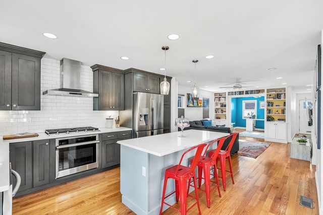 a large kitchen with a stove a sink dishwasher a refrigerator and a dining table with wooden floor