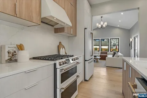 a kitchen with stainless steel appliances granite countertop a stove and white cabinets with wooden floor