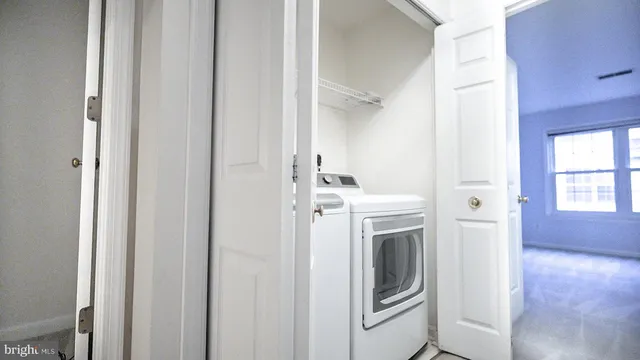 a view of a hallway with wooden floor and a bathroom