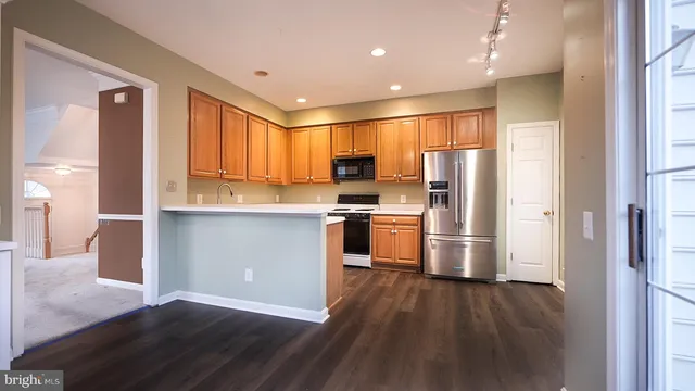 a kitchen with stainless steel appliances a refrigerator and wooden floor