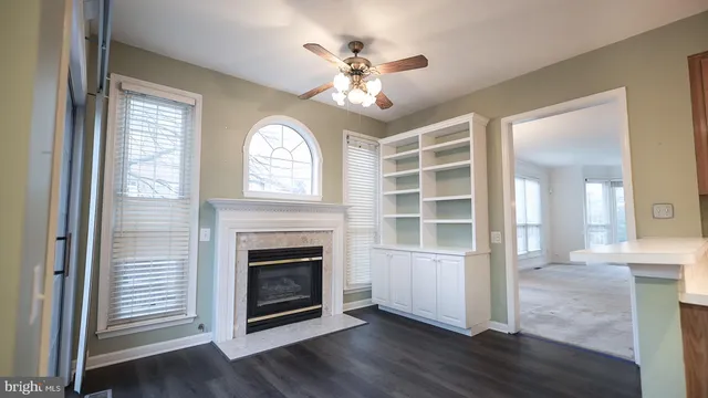a view of an empty room with wooden floor fireplace and a window