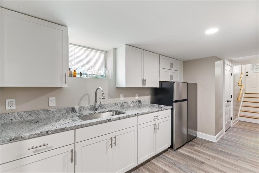 17 Old Essex Road Manchester, MA 01944 - Photo 32 of 40 a kitchen with a sink dishwasher a refrigerator and white cabinets with wooden floor