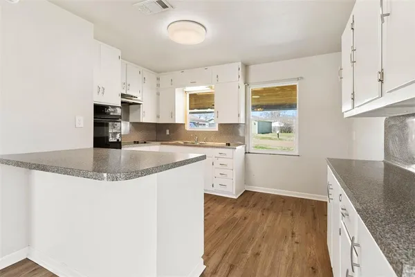 a kitchen with stainless steel appliances granite countertop a sink a stove a refrigerator and cabinets with wooden floor