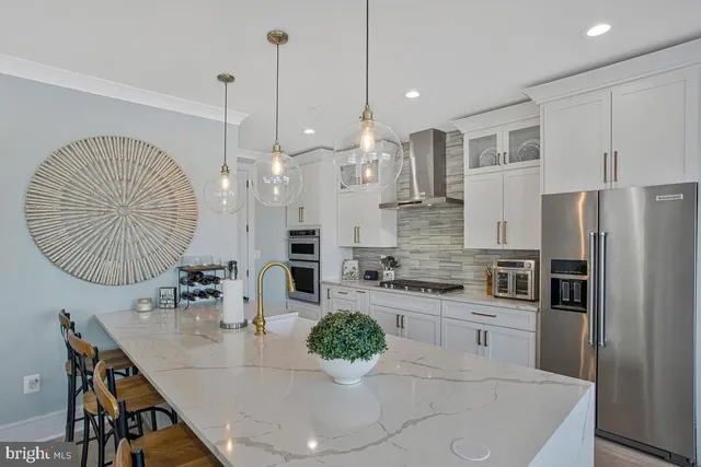 a kitchen with stainless steel appliances kitchen island granite countertop a table chairs and a refrigerator