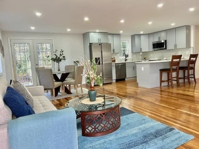 a living room with stainless steel appliances kitchen island granite countertop a couch dining table and chairs