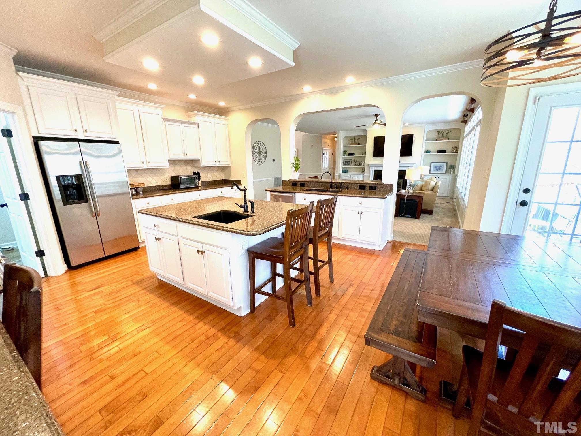 115 Beckford Road Cary, NC 27518 - Photo 21 of 50 a kitchen with stainless steel appliances granite countertop a stove top oven a sink a dining table and chairs with wooden floor