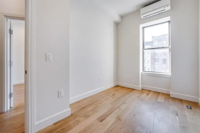 an empty room with wooden floor closet and windows