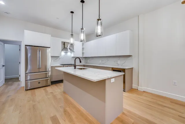 a kitchen with stainless steel appliances granite countertop a sink a stove a refrigerator and island with wooden floor