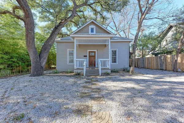 a front view of a house with a yard and large tree