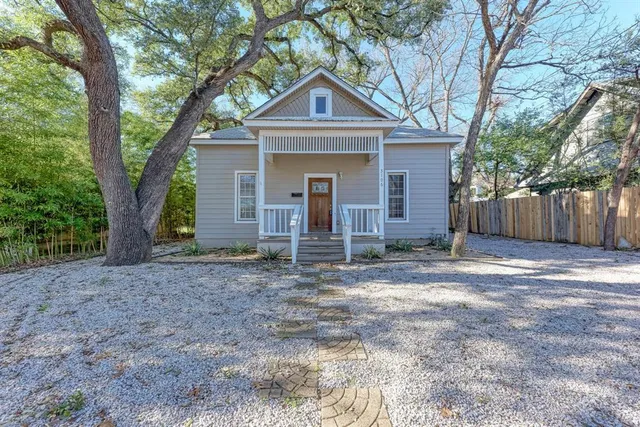 a front view of a house with a yard and large tree
