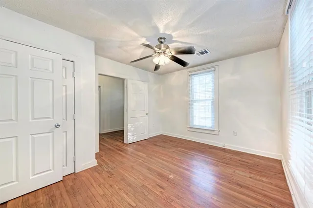 a view of an empty room with a window and wooden floor