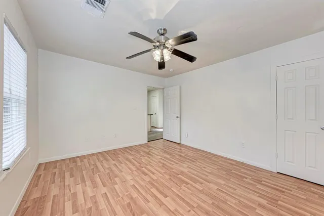 a view of empty room with wooden floor and fan