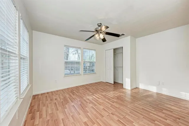 a view of empty room with wooden floor and fan