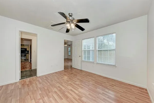 a view of an empty room with wooden floor and a window
