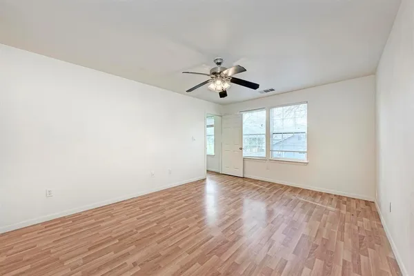 an empty room with wooden floor and windows