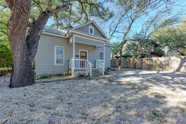 a view of a house with a yard and large tree
